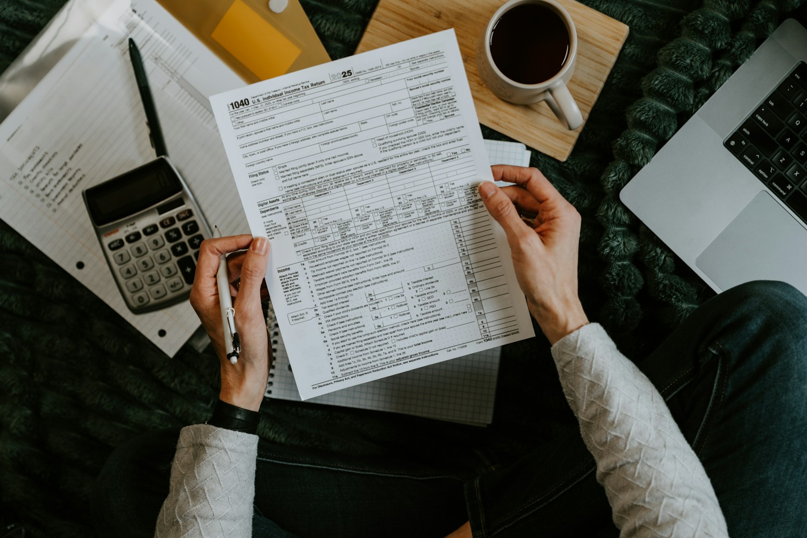 Mans revisant formularis laborals amb calculadora i portàtil